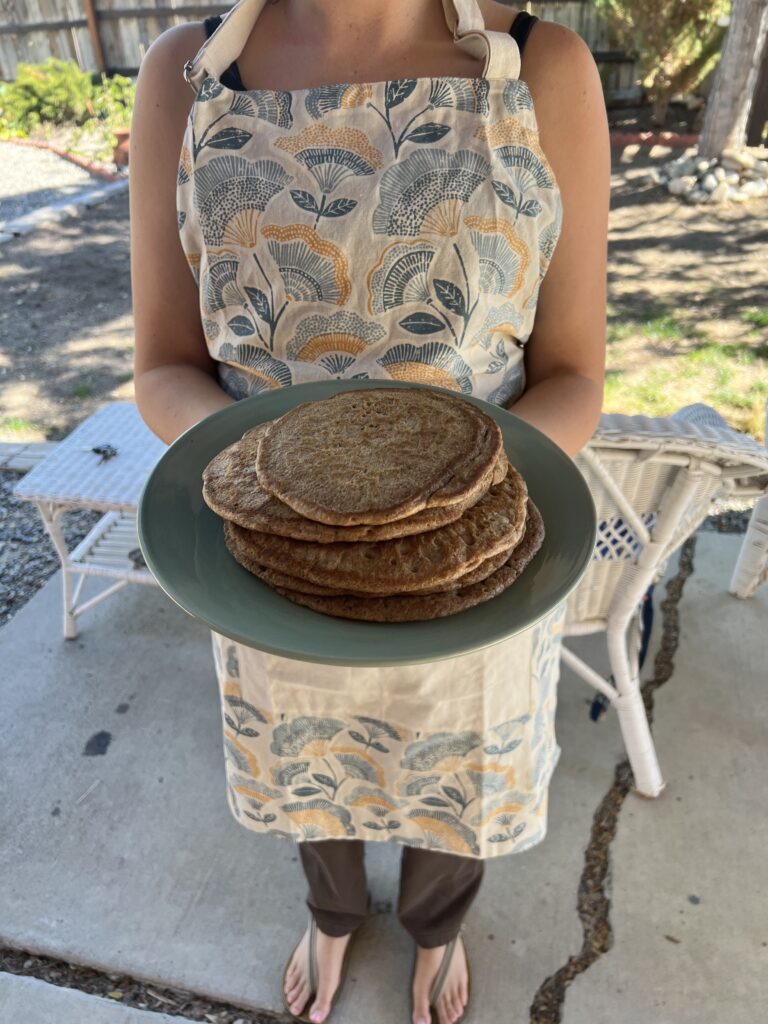 Girl holding a stack of acorn pancakes outside.
