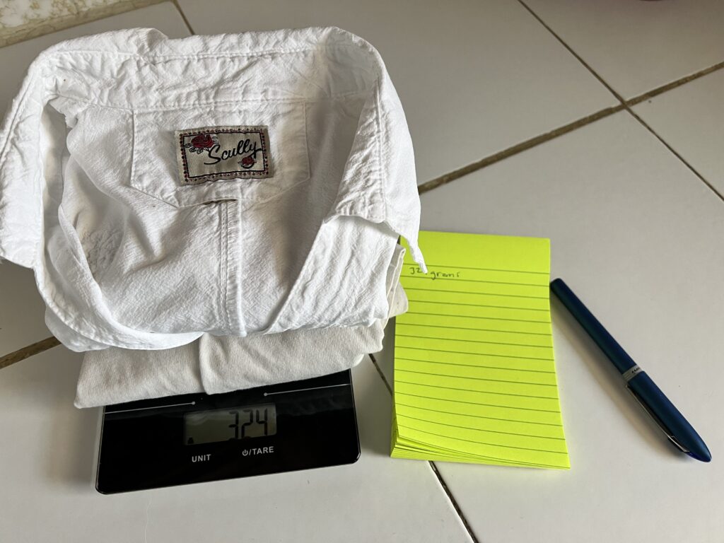 Two white shirts being weighed in grams.