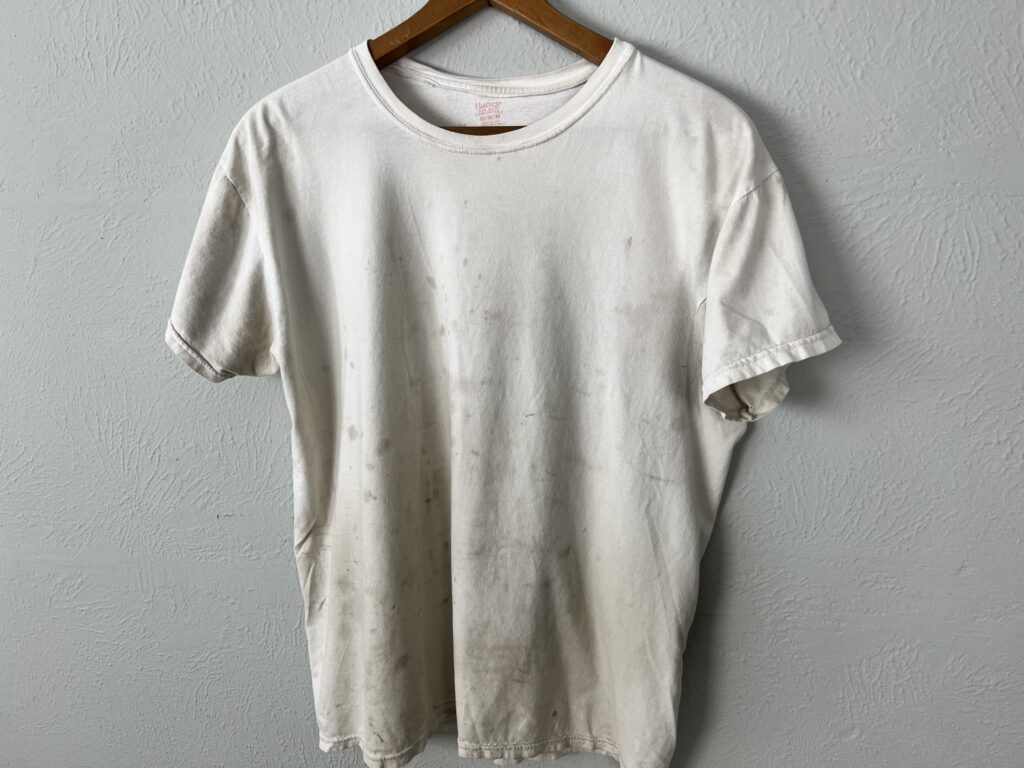 A white stained cotton shirt hanging on wall.