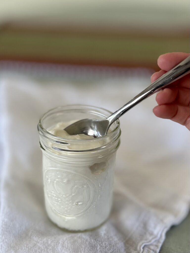 A close up of Yogurt in mason jar with spoon.