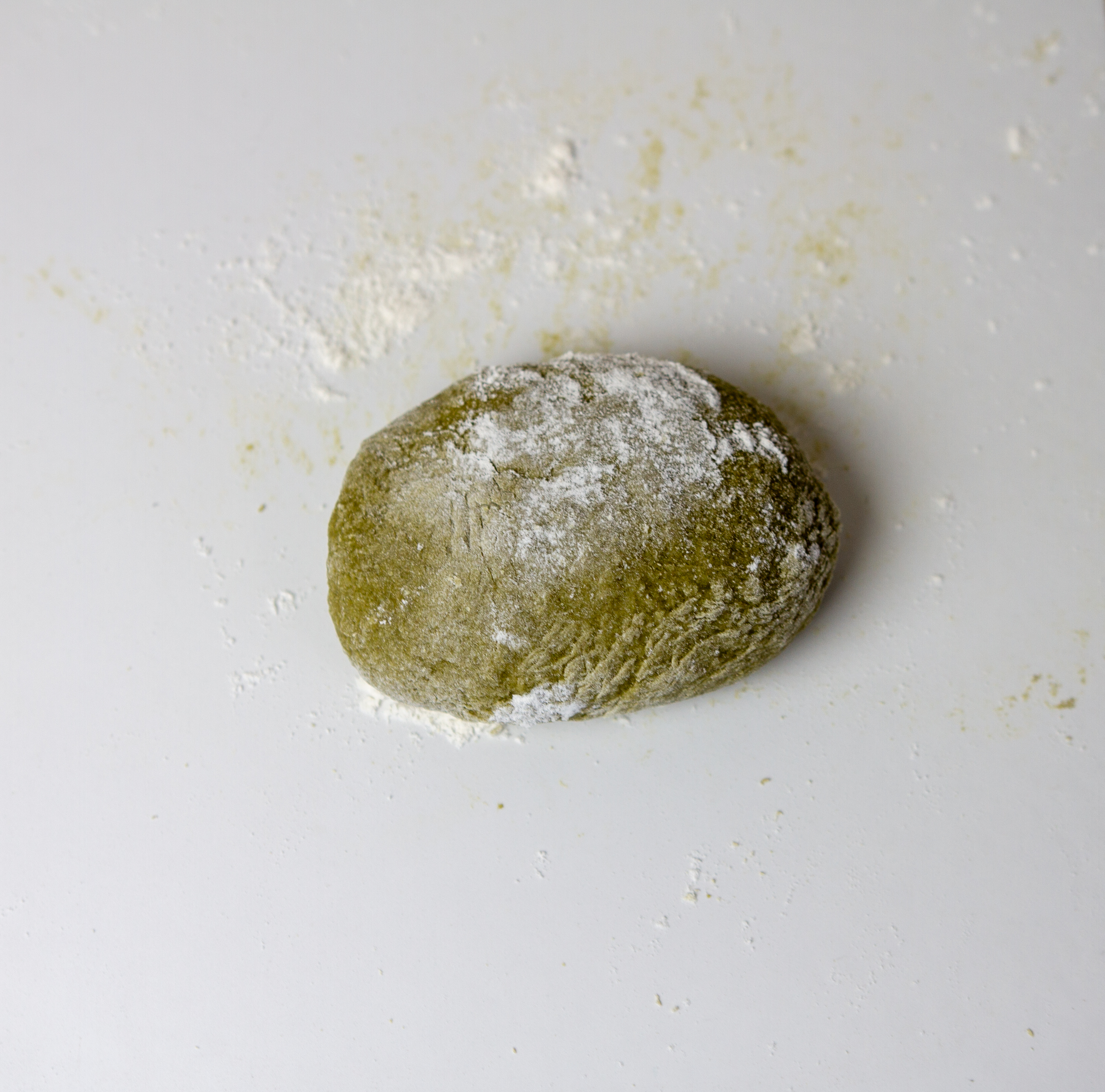 Nettles pasta dough on floured surface in process of kneading.