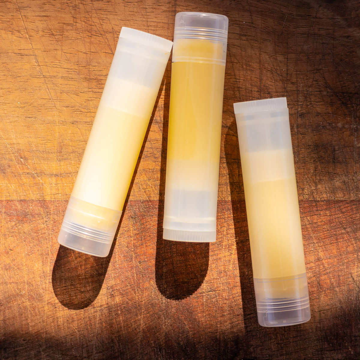 Tallow Lip Balm on wooden cutting board with warm lighting.