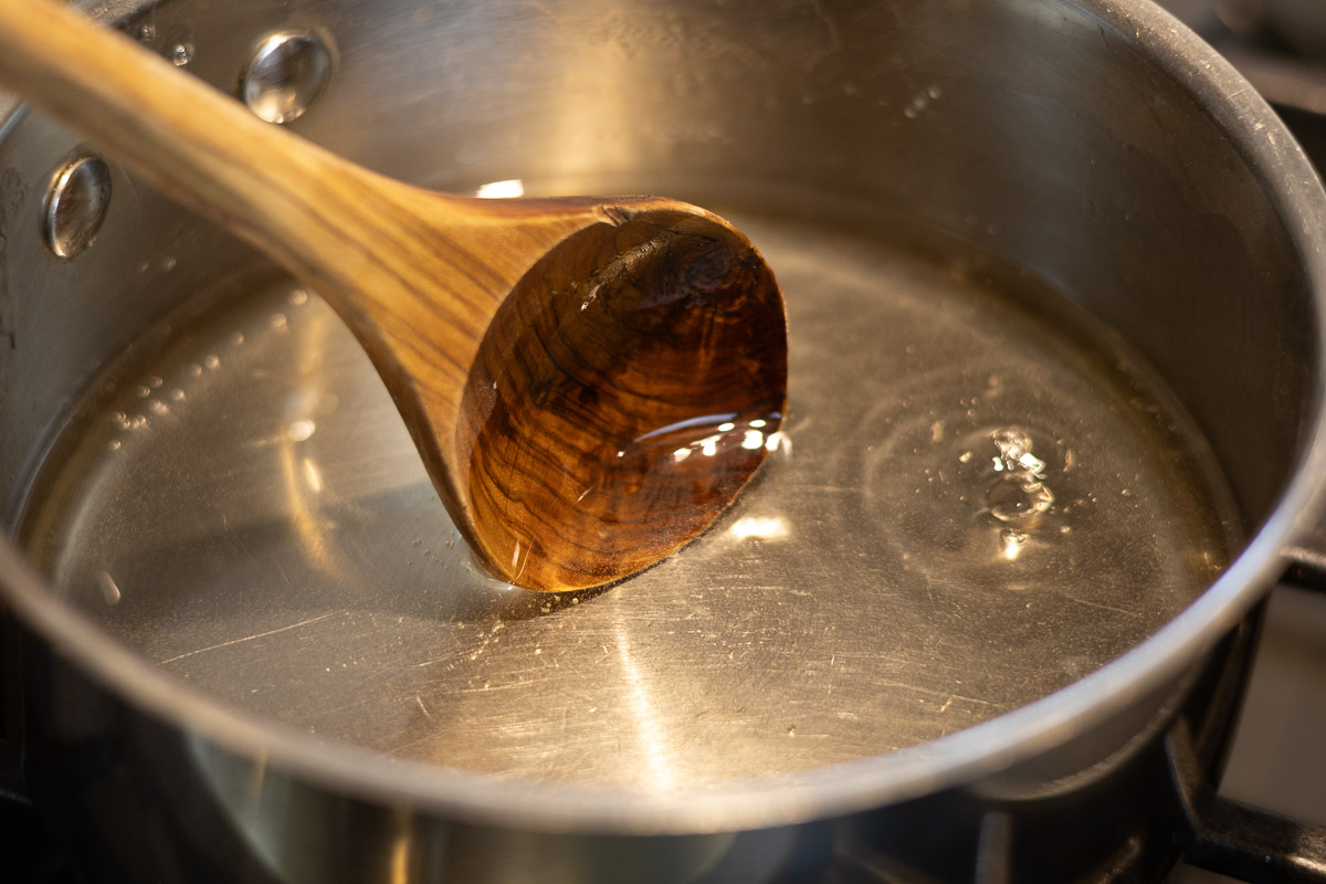 A silver pot and wooden spoon stirring the contents. 