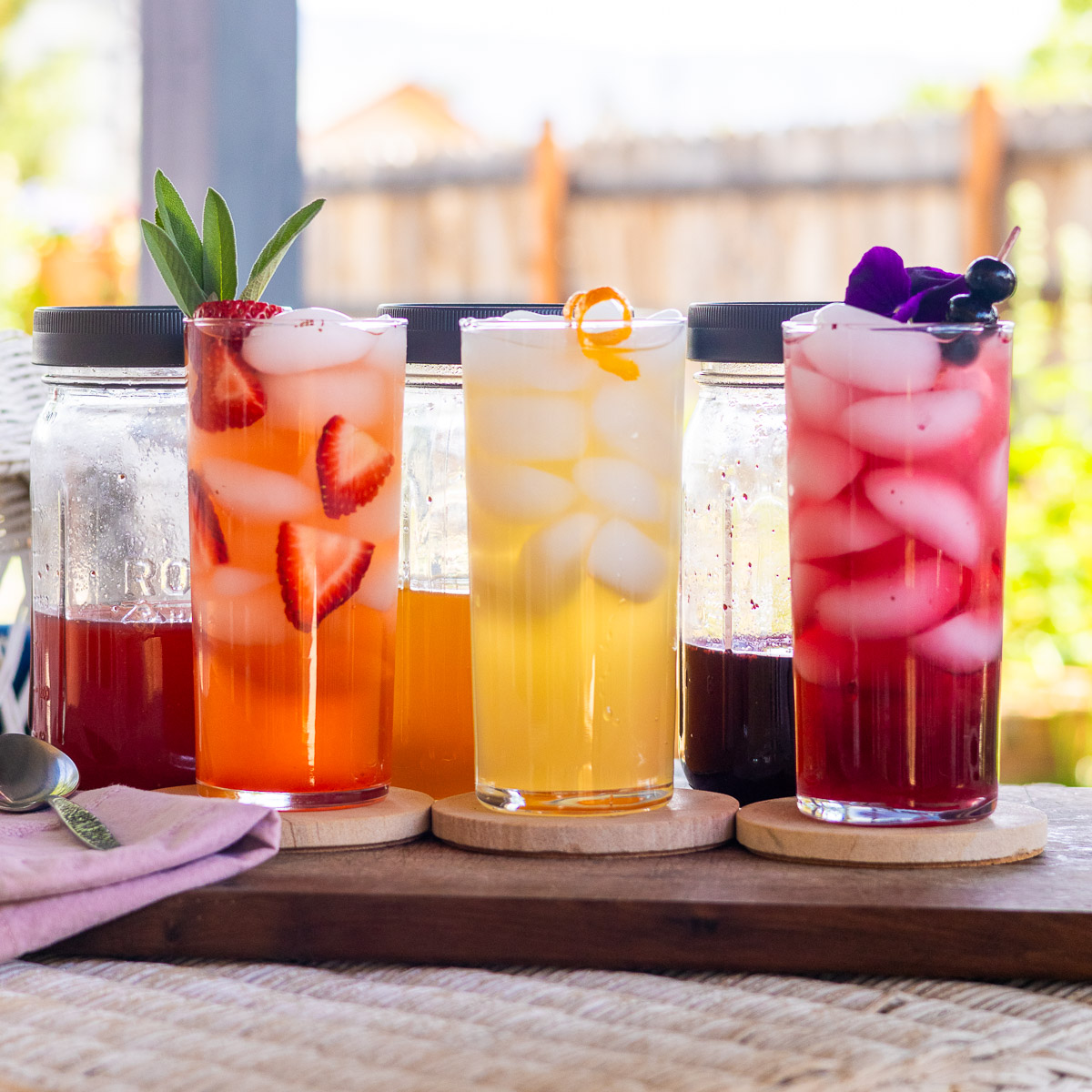 One each of strawberry, Orange, and Blueberry shrub on a wicker table.