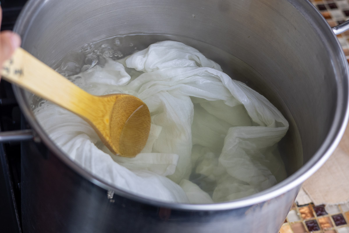 Scouring cotton fabric in silver pot and stirred by wooded spoon.