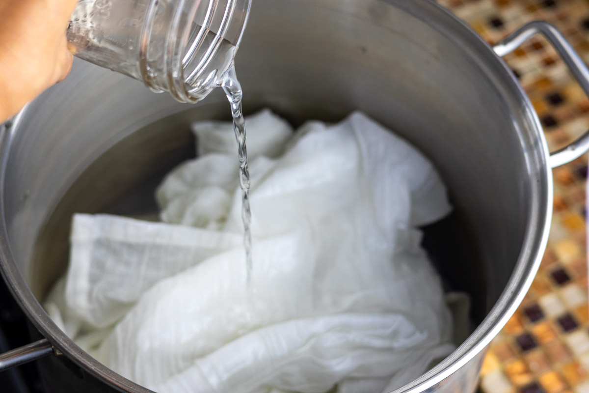 Pouring scouring liquid in silver pot with a white cotton textile.