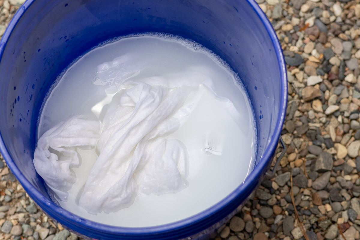 A blue five gallon bucket with chalk and mordanted cotton.