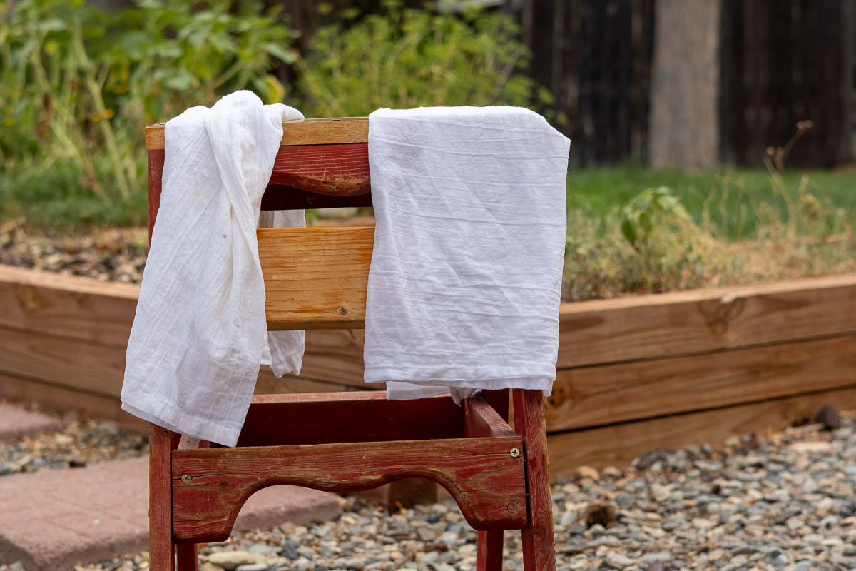 two finished mordanted cotton pieces drying on a small wooded later outdoors.