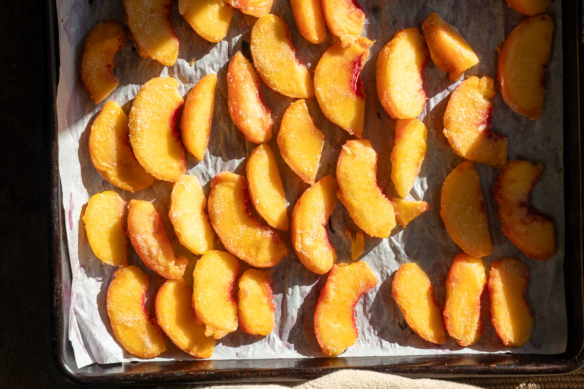 Peaches slices that are frozen on cookie sheet.