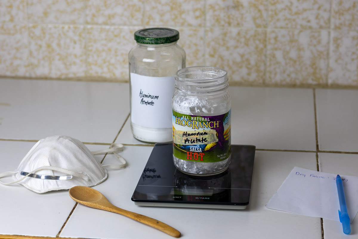 aluminum acetate being measured out next to a safety mask and spoon.