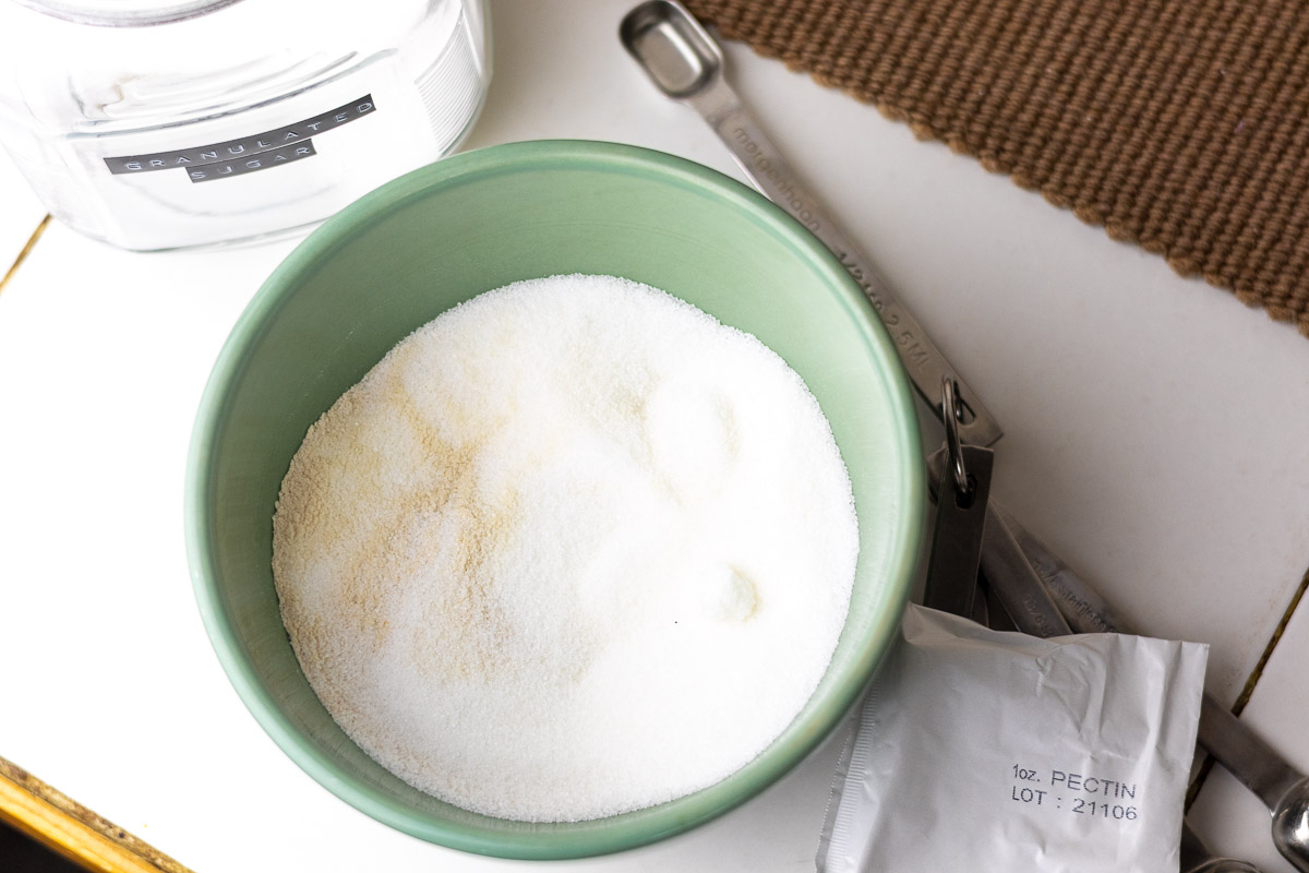 A green bowl with sugar and pectin mixed in.