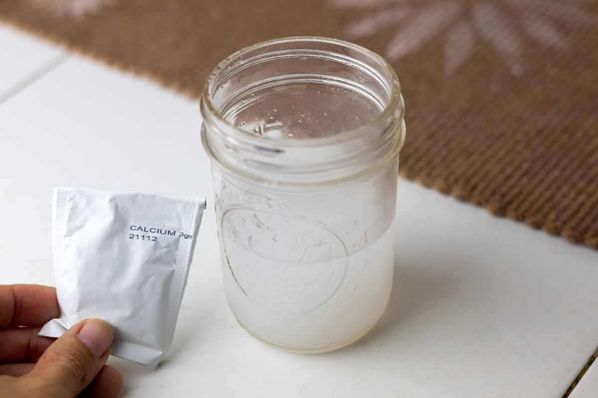 A hand holding calcium powder next to a jar.