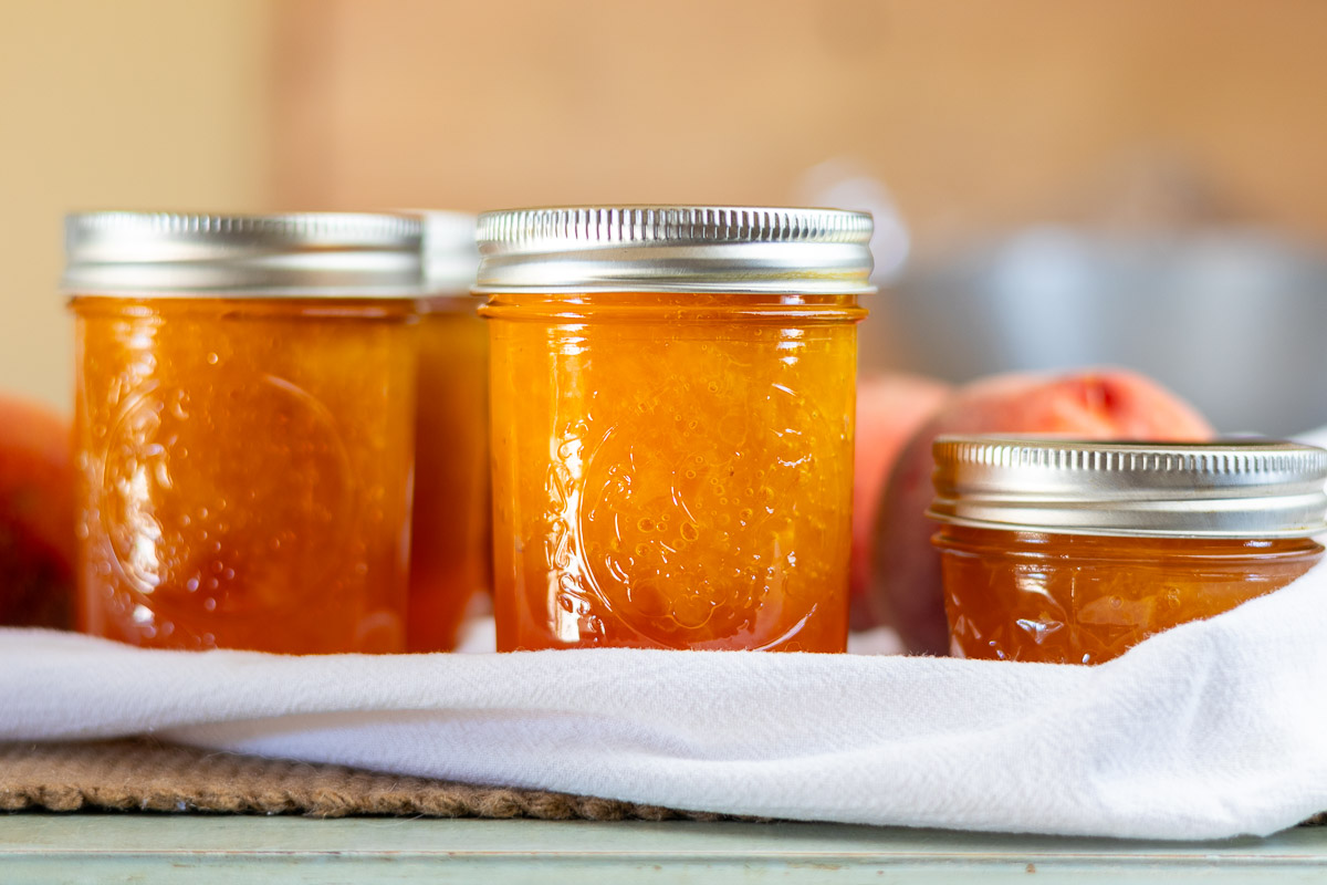 jars of low sugar peach jam on table.