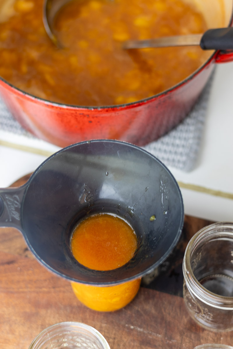 A canning funnel used to ladle peach jam in jar.