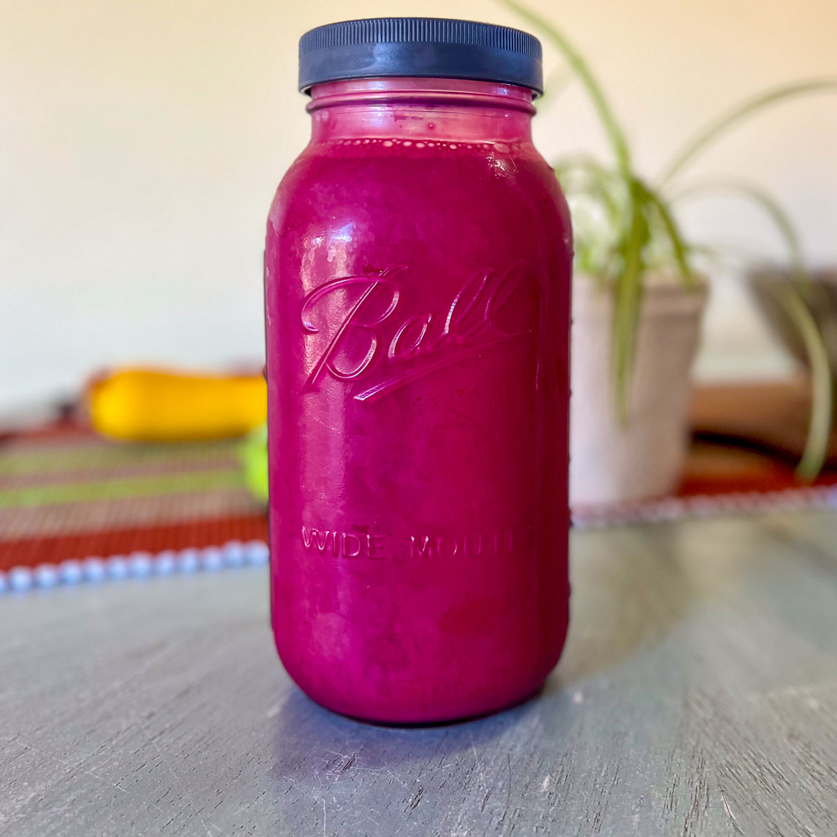 A close up finished magenta-purple chokecherry juice in half-gallon mason jar.