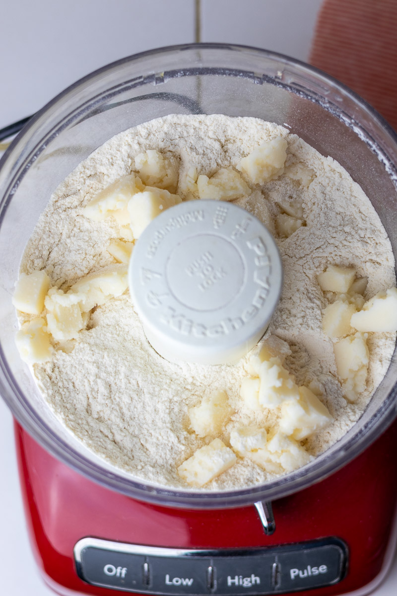 Lard chunks added to pie crust ingredients in food processor.