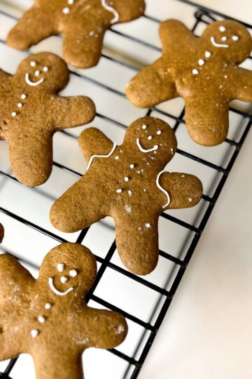 Iced sourdough gingerbread cookies cooling on a rack.