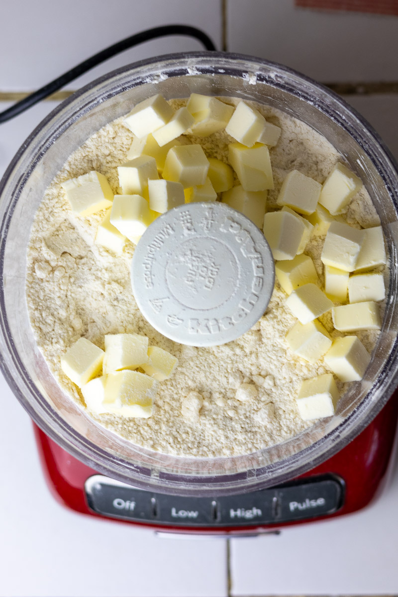 butter cubes added to pie crust ingredients in food processor.