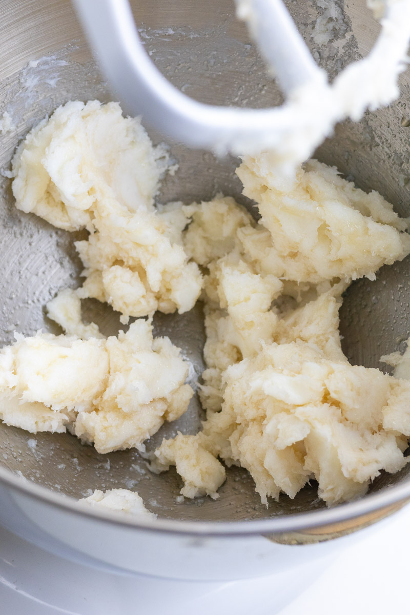 A close up of lard, sugar and other cookie ingredients being mixed in a stand mixer.