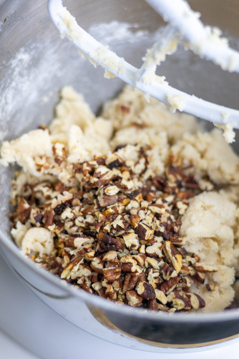A mixing bowl with cookie batter and finely cut pecans.