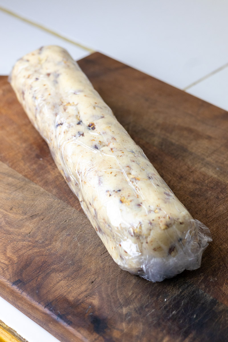 A maple pecan sandie cookie log on a cutting board.