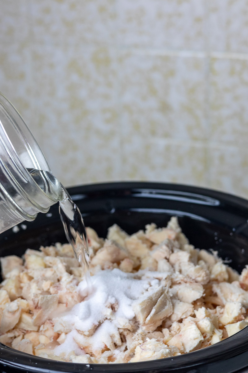 Water being poured into a crockpot full of suet to do the wet rendering tallow process.
