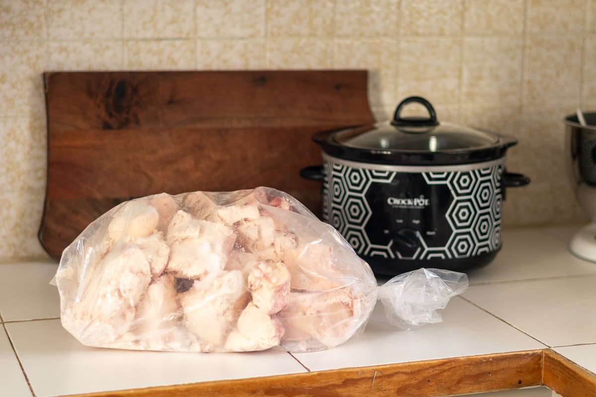 A bag of unprocessed suet in kitchen next to a crockpot.