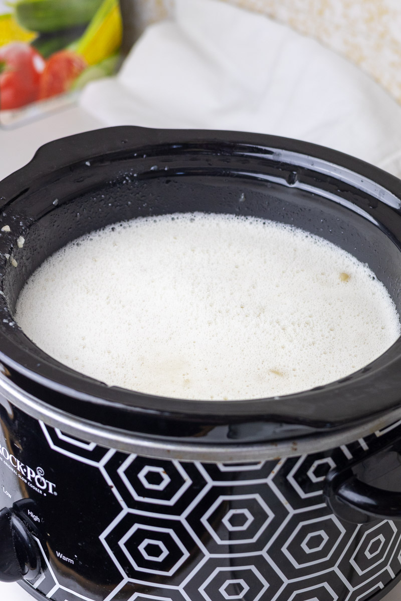 Blended fat and water in a crockpot, showing the foam on top.