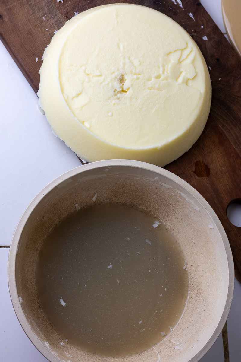 A layer of wet rendered tallow next to a bowl of water full of impurities.