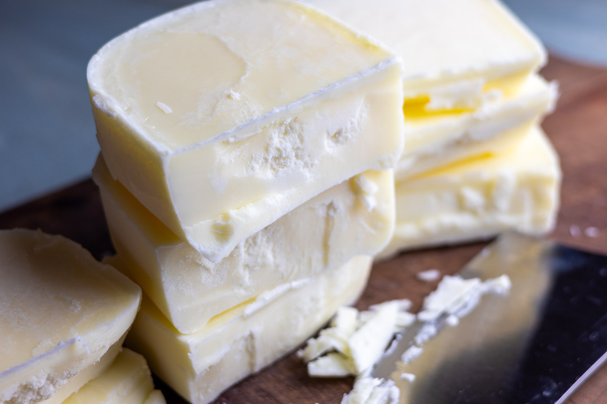 A close up of tallow blocks showing texture next to a chef's knife.