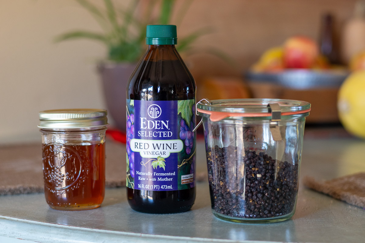 Honey, red wine vinegar, and dried elderberries on a dining room table.