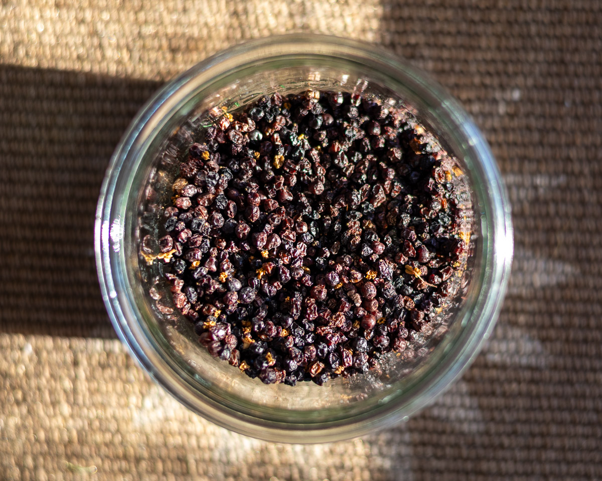 An overhead shot of dried elderberries in a jar with shadow.