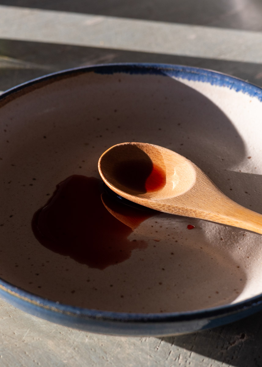 A ceramic plate with bamboo spoon, showing the elderberry oxymel on it.