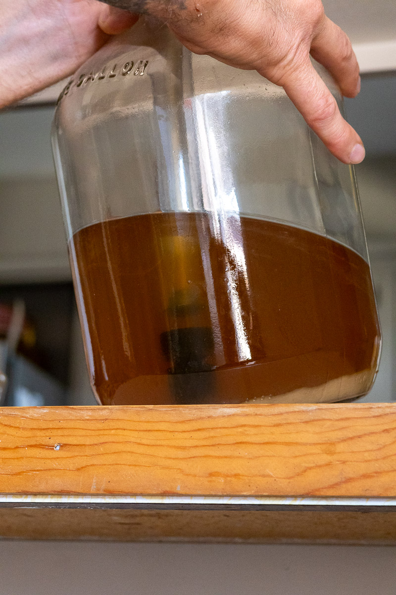 Two hands, using an auto siphon to rack mead.