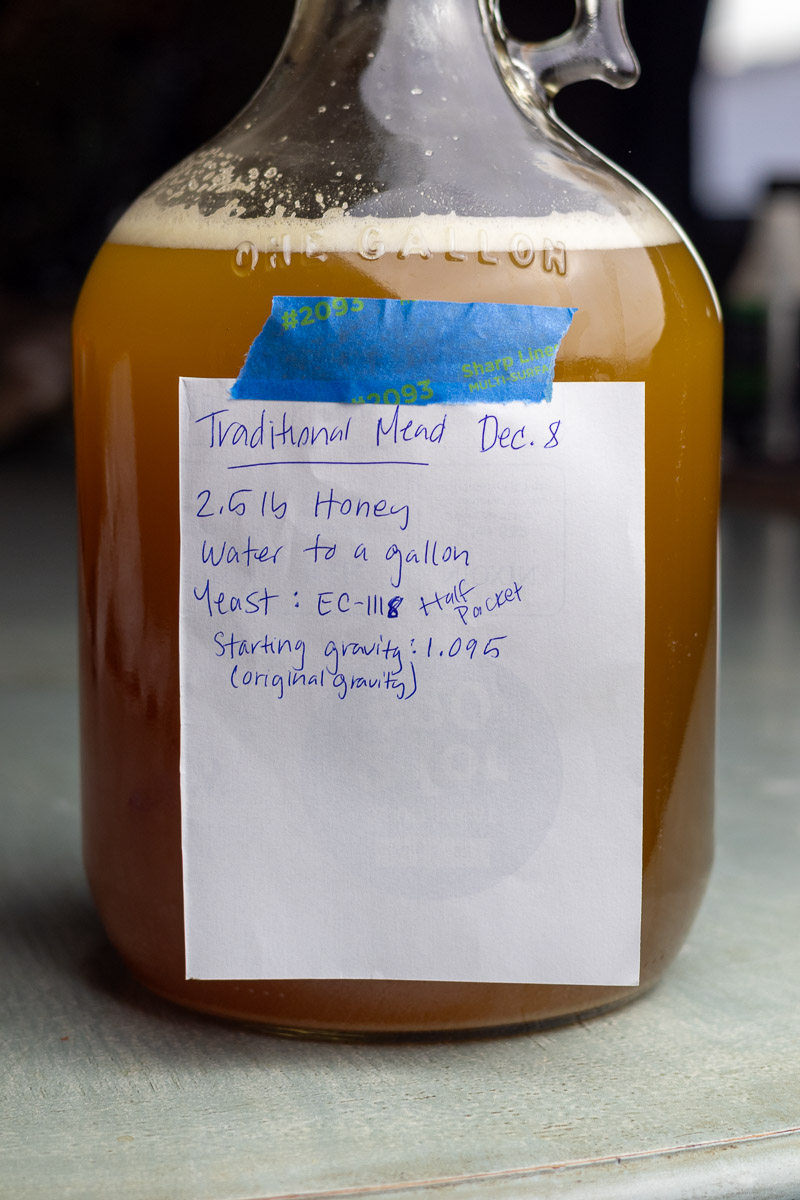 A gallon carboy showing a label with ingredients and other information for mead.