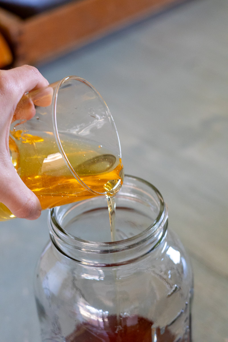A hand showing agave being poured in marigold infused vodka.