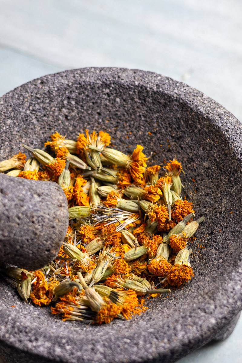 Whole marigold flowers in mortar and pestle.