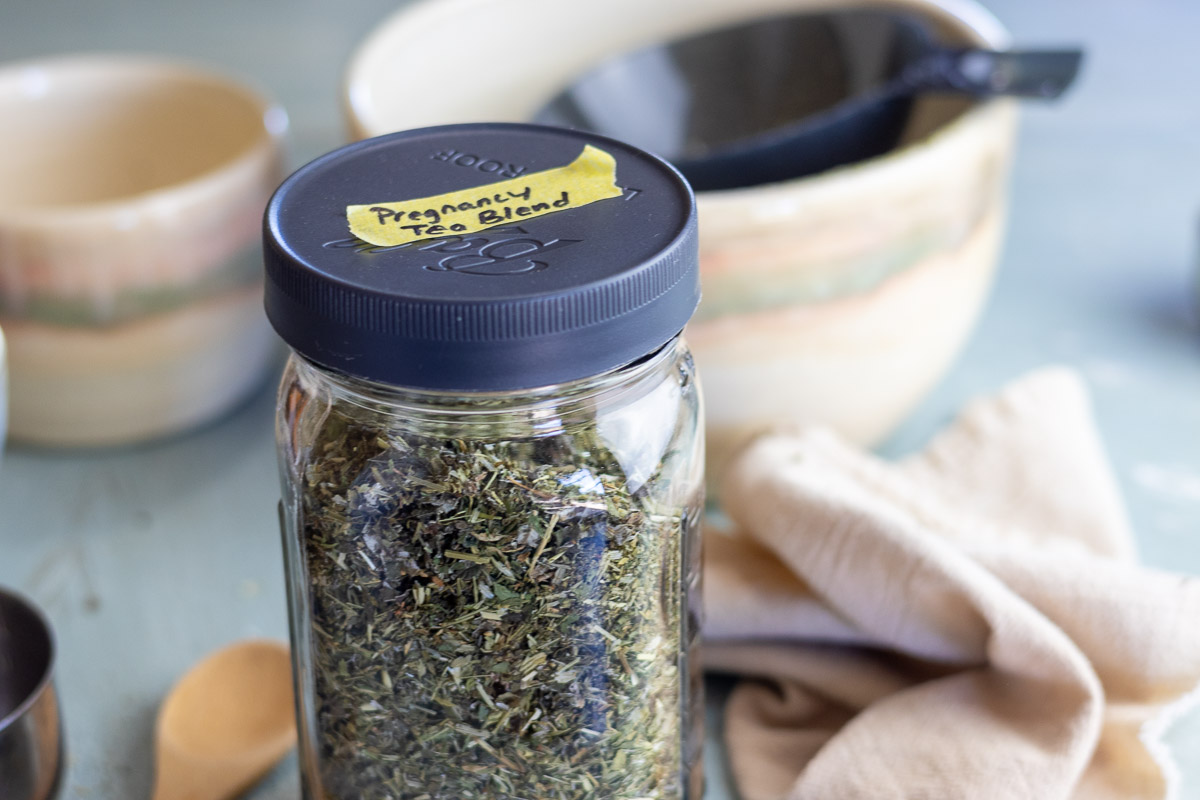 A labeled mason jar of Nora tea blend with mixing bowls in background.